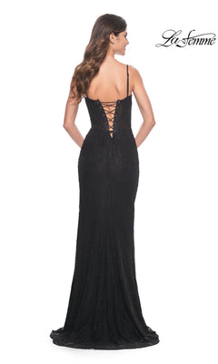 A woman in the La Femme Lace-Up Back Long Lace Prom Dress 32237, featuring black lace, thin straps, and a lace-up back, stands facing away from the camera.