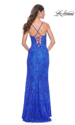 A woman wearing the La Femme Floral-Lace Long Corset Prom Dress 32248, featuring blue lace, thin cross-back straps, a corset-style bodice, and a lace-up back detail, stands with her back to the camera.