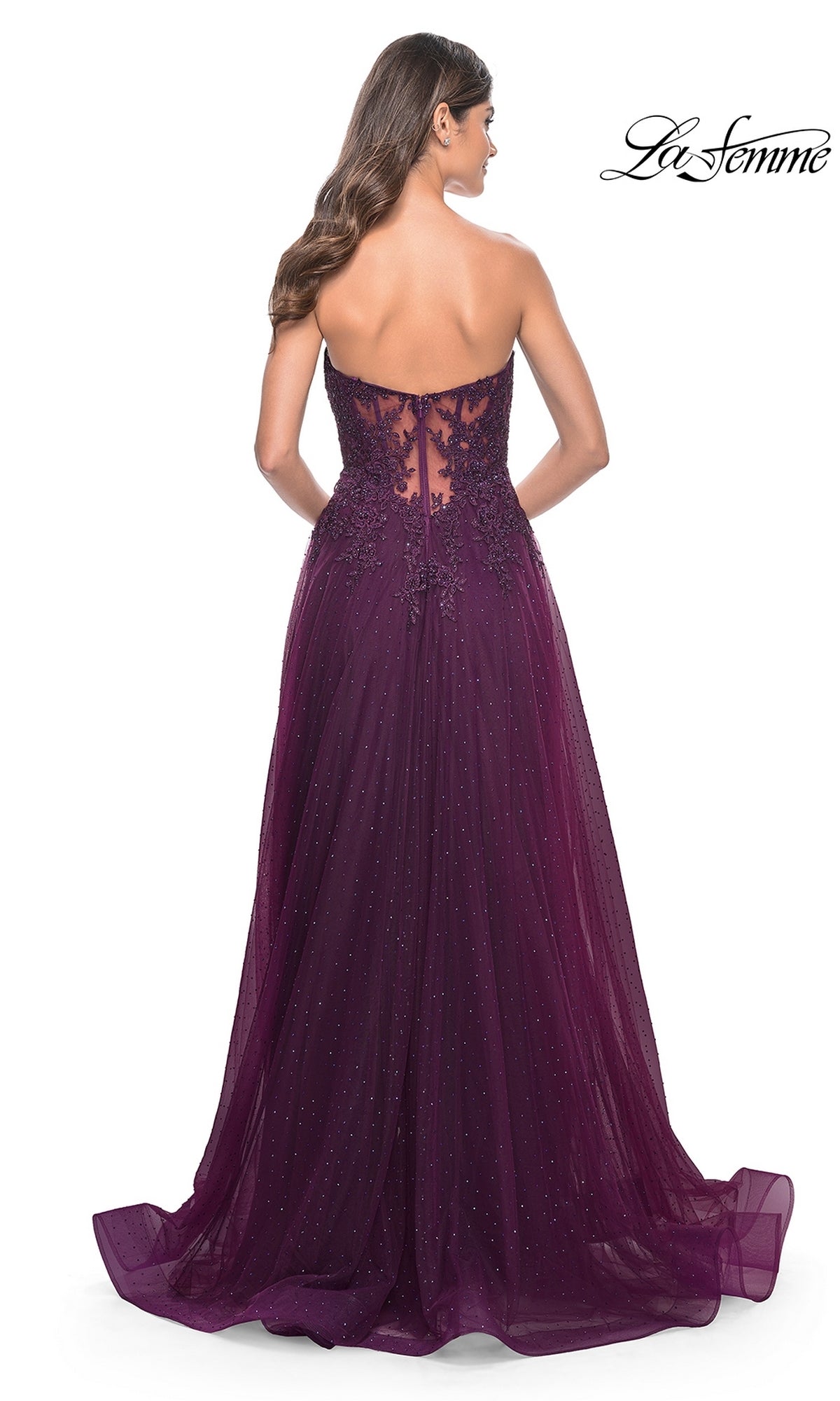 A woman models the La Femme Sheer-Lace Long Beaded Prom Dress 32253—floor-length, dark purple, strapless with a sheer lace back and subtle sparkles—posing against a white background.