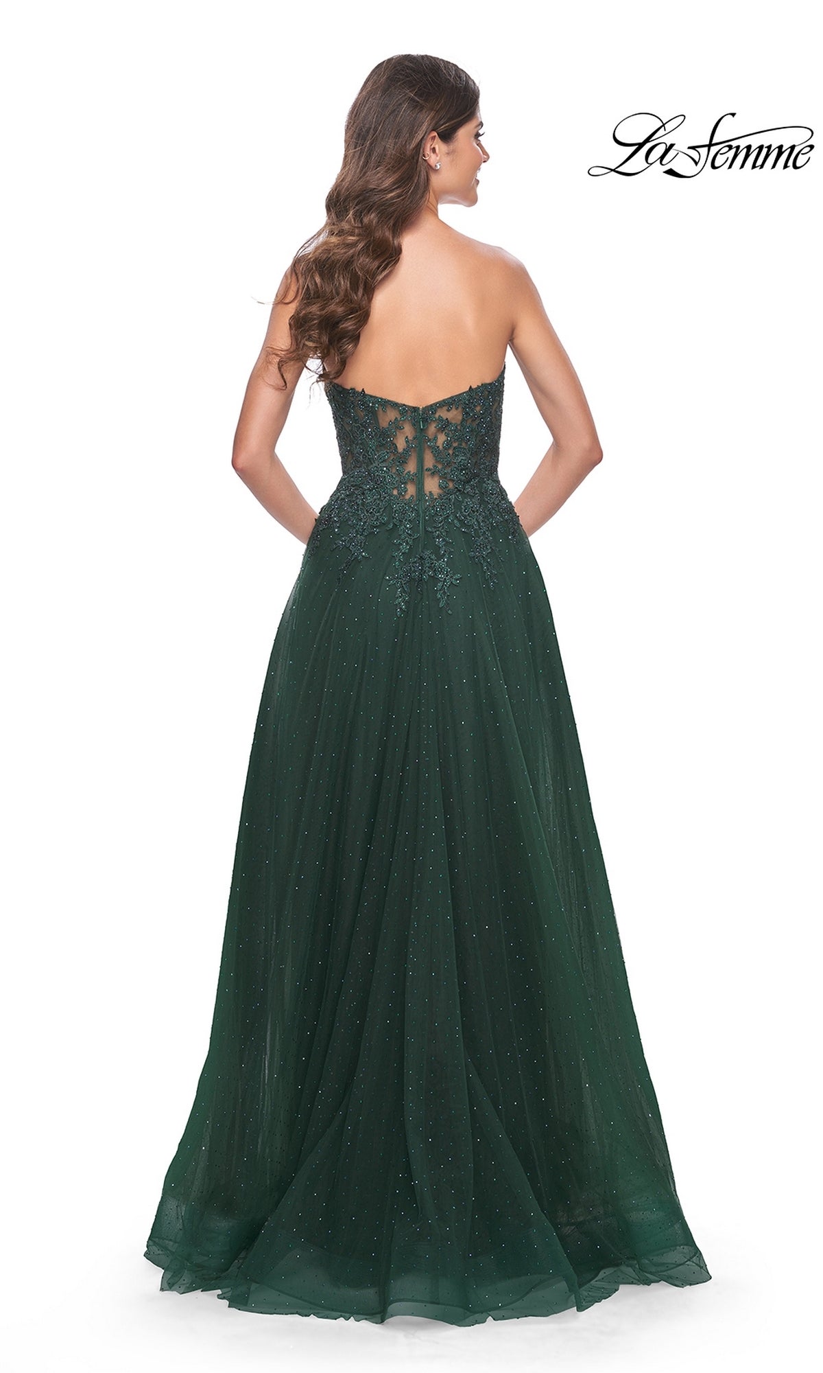 A woman with long wavy hair models the La Femme Sheer-Lace Long Beaded Prom Dress 32253 in dark green, strapless with lace and bead details, shown from the back. The La Femme logo is displayed in the top right corner.