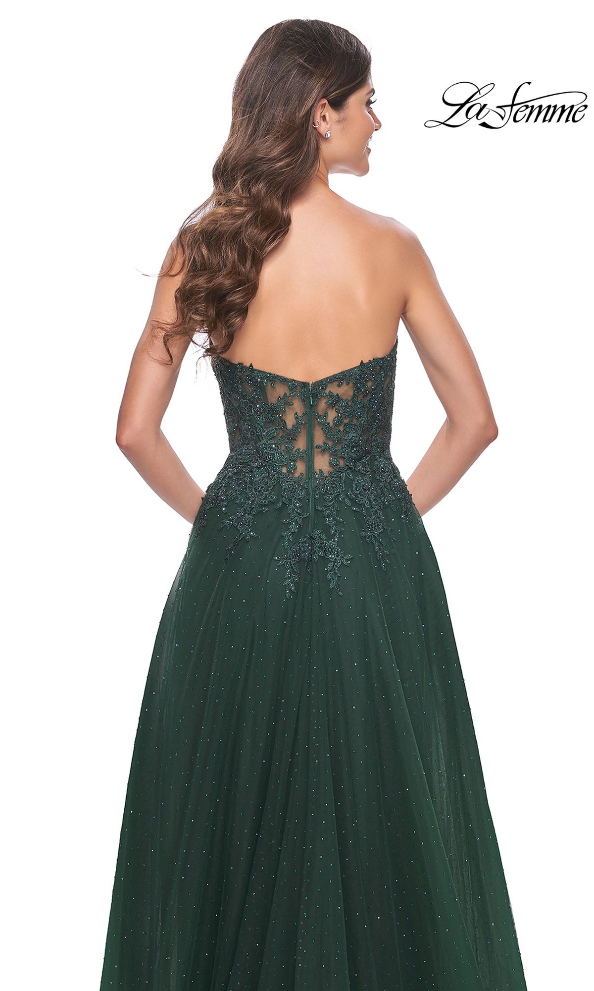 Woman in the La Femme Sheer-Lace Long Beaded Prom Dress 32253, a dark green strapless gown with lace and sequin detailing on the back, stands facing away from the camera.