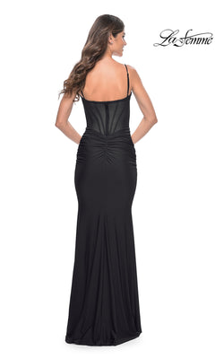 Woman in the La Femme Sheer-Back Long Corset Prom Dress 32257, featuring spaghetti straps and back ruching, stands facing away from the camera. The La Femme logo is in the top right corner.