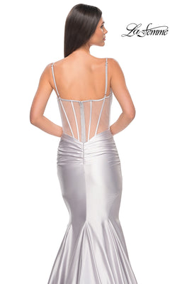 A woman stands with her back to the camera in a form-fitting silver La Femme Long Corset Mermaid Prom Dress 32269, featuring spaghetti straps and a sheer back panel. The "La Femme" logo appears in the top right corner.