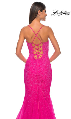 A woman models the La Femme Embellished Long Mermaid Prom Dress 32273 in bright pink, featuring a fitted silhouette, sparkling embellishments, and a crisscross lace-up back, shown from behind.