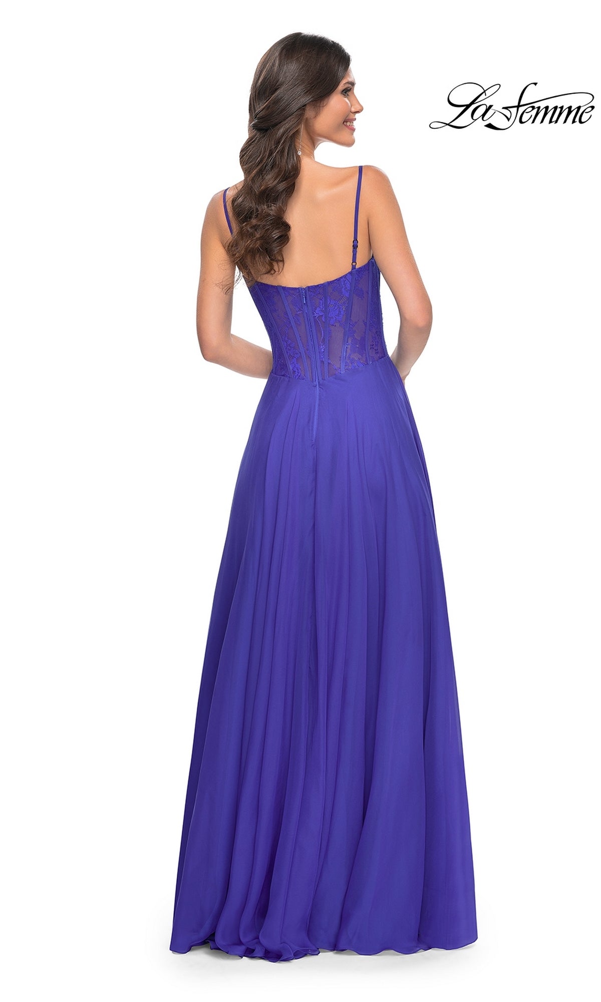 A woman stands with her back to the camera in the La Femme Long Chiffon Sweetheart Prom Dress 32276, a floor-length, sleeveless purple gown featuring a floral-lace sweetheart bodice. The La Femme logo appears in the top right corner.