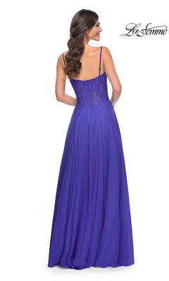 A woman stands with her back to the camera in the La Femme Long Chiffon Sweetheart Prom Dress 32276, a floor-length, sleeveless purple gown featuring a floral-lace sweetheart bodice. The La Femme logo appears in the top right corner.