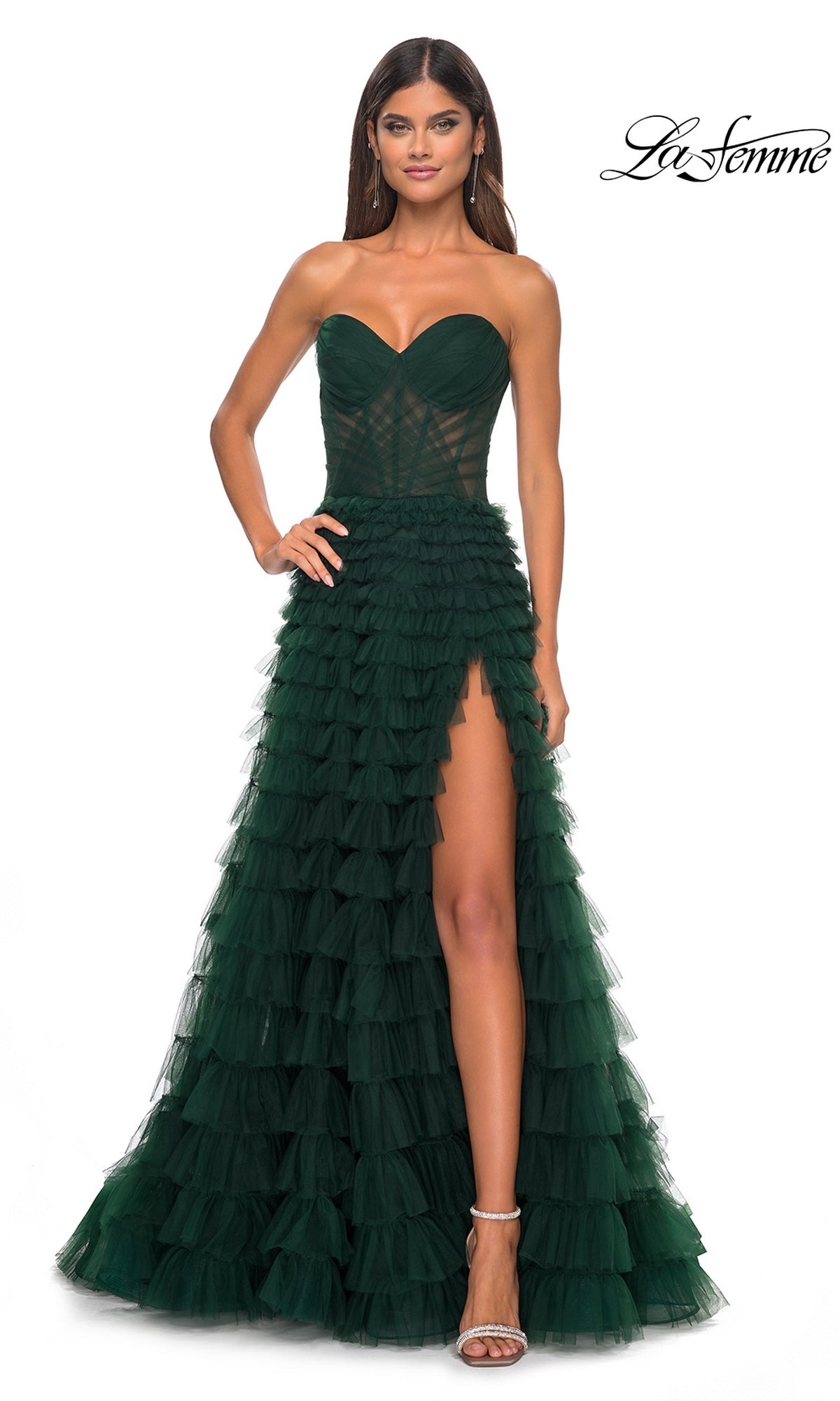 A woman models the La Femme Strapless Long Ruffled Prom Dress 32283 in dark green tulle with A-line ruffled layers, sweetheart neckline, and high slit, posed elegantly against a plain white background.