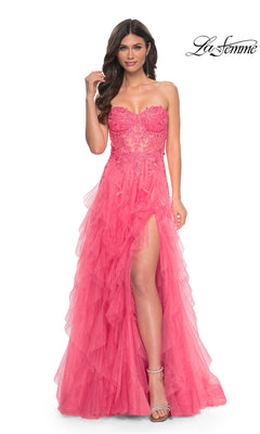 A woman models the La Femme Strapless Long Coral Prom Dress 32286, featuring a ruffled skirt, beaded lace bodice, and high slit, standing against a white background.