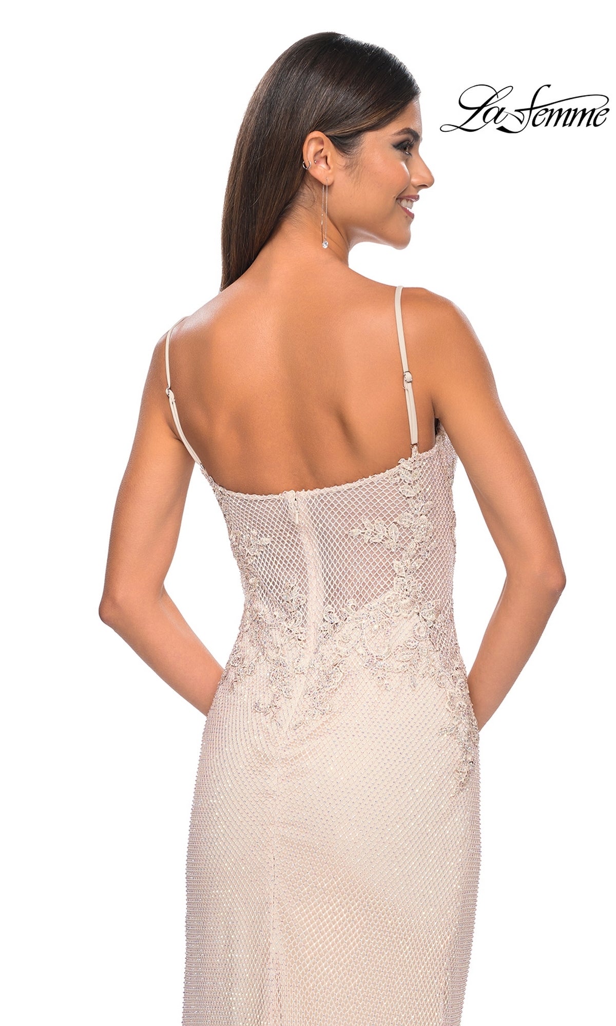 A woman in a light-colored La Femme Embellished Long Fishnet Prom Dress 32292 with spaghetti straps stands facing away, showing off its beaded lace details and fitted back. The La Femme logo appears in the top right corner.