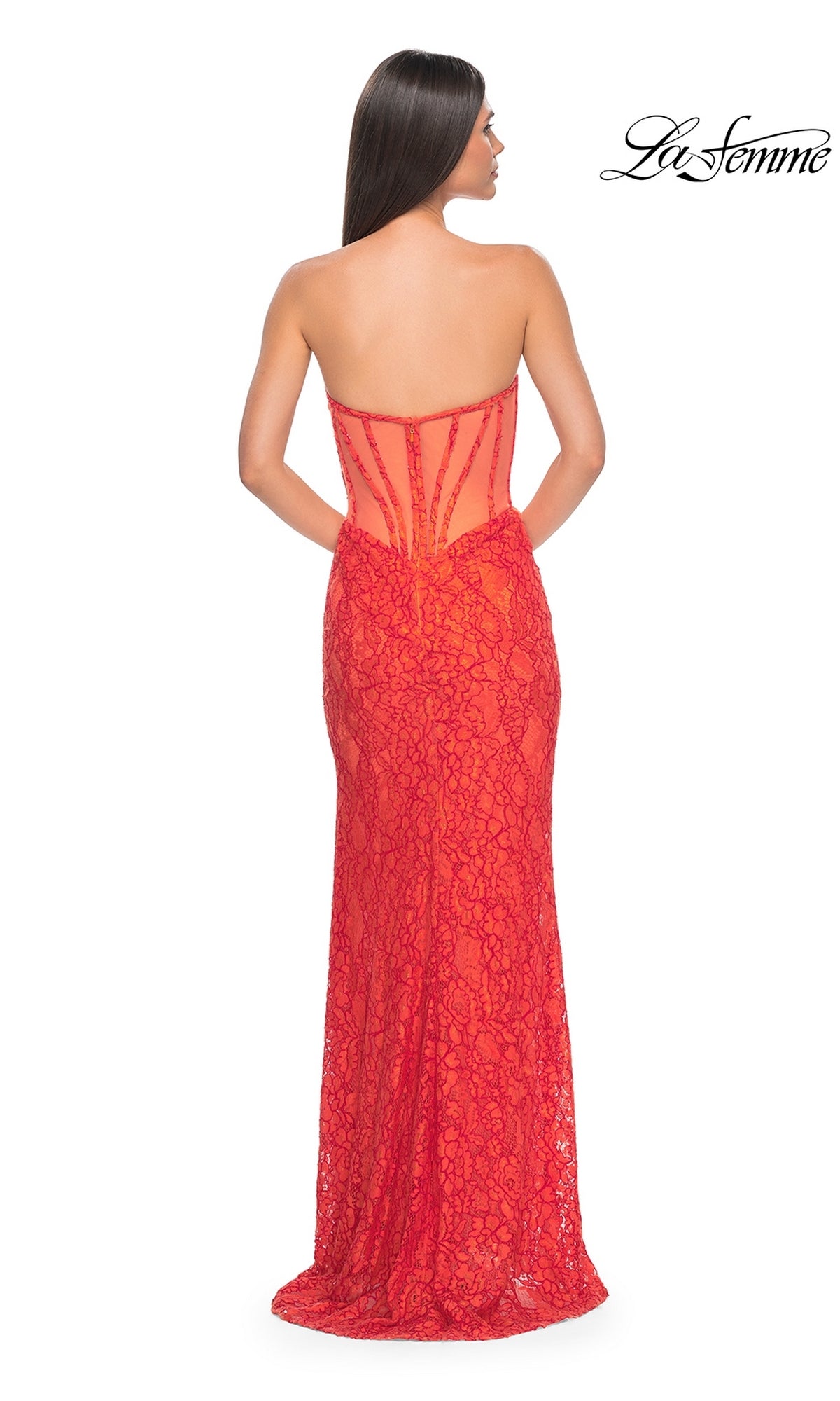 A woman stands with her back to the camera in the La Femme Strapless Long Lace Prom Dress 32298, a floor-length red gown featuring a sheer back panel. The 