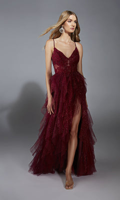 A woman wears the Aerie Couture 322 Glitter Ruffle Prom Ball Gown, a sleeveless deep burgundy dress with sparkly embellishments, high leg slit, thin straps, and layered tulle skirt, posing against a plain gray background.