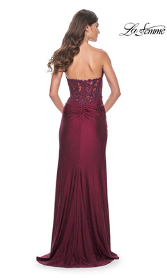 Woman wearing the La Femme Strapless Long Pleated Prom Dress 32301, a floor-length burgundy gown with a pleated design, seen from the back. The "La Femme" logo appears in the top right corner.
