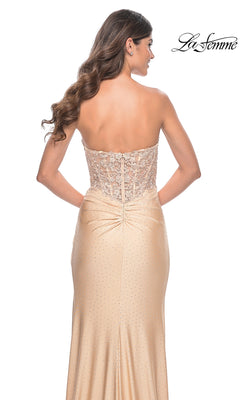 Woman wearing the La Femme Strapless Long Pleated Prom Dress 32301 in beige, featuring a lace-up back and floral-lace bodice with beaded details, photographed from behind.