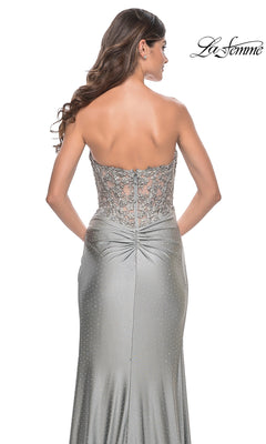 A woman faces away, wearing the La Femme Strapless Long Pleated Prom Dress 32301 with a silver floral-lace bodice and embellished back.