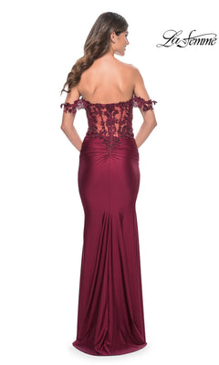 Shown from behind, a woman models the La Femme Off-the-Shoulder Long Prom Dress 32302 in burgundy, featuring beaded floral lace detailing and a fitted, ruched back. The La Femme logo is visible in the top right corner.