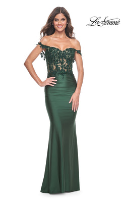 A woman poses with one hand on her hip in the La Femme Off-the-Shoulder Long Prom Dress 32302, a dark green gown featuring beaded floral lace on the bodice, set against a white background.