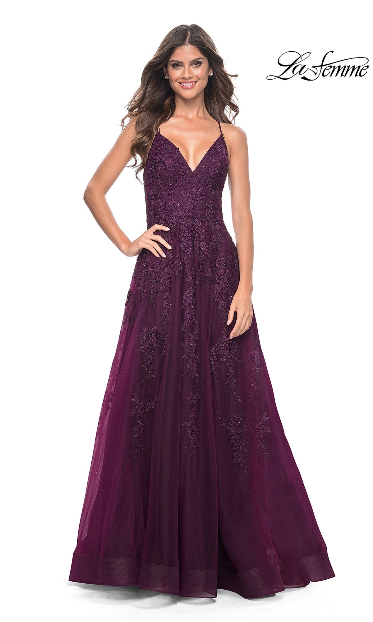 Woman wearing the La Femme Long Lace A-Line Prom Dress 32303 in deep purple, featuring sleeveless floral lace and floor-length style, poses and smiles against a white background; 