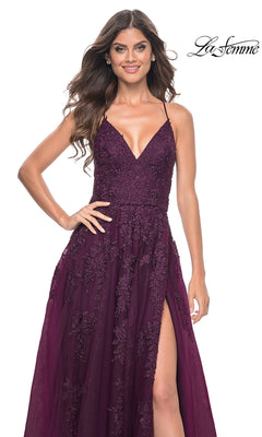 A woman stands smiling against a white background wearing the La Femme Long Lace A-Line Prom Dress 32303, featuring a sleeveless deep purple design with a V-neckline and high slit. The "La Femme" logo appears in the top right corner.
