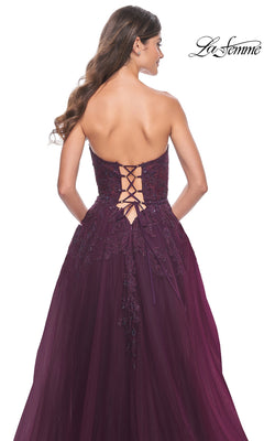 A woman wearing the La Femme Lace-Up Long Sweetheart Prom Dress 32304 in deep purple, featuring a strapless design, embroidered detailing, and a lace-up back, is shown from behind.