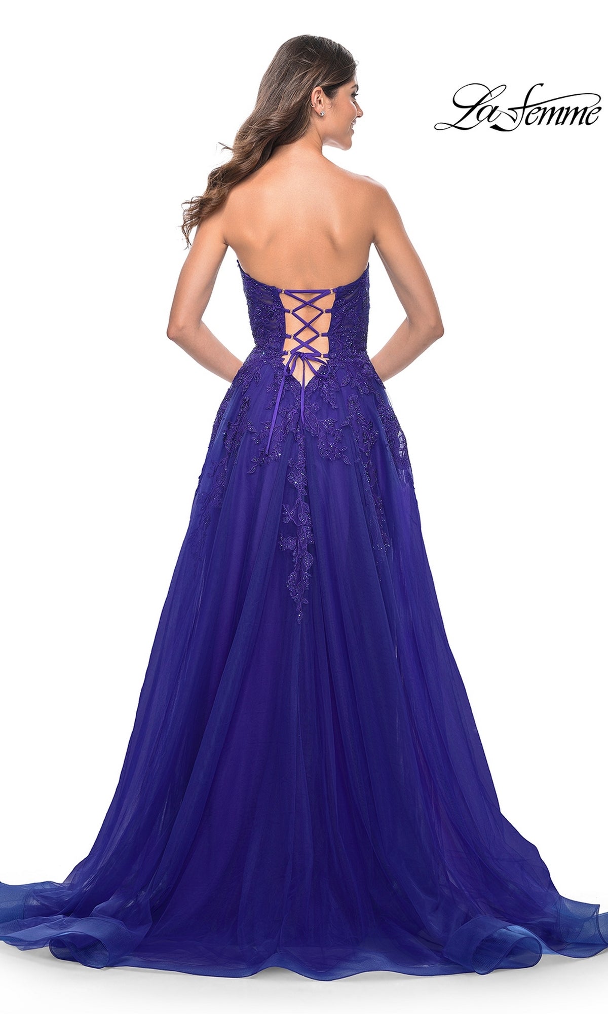 A woman stands with her back to the camera, showcasing the elegant silhouette and lace-up back of the La Femme Lace-Up Long Sweetheart Prom Dress 32304, a strapless A-line gown featuring embroidery detail.