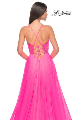 Woman wearing the La Femme Lace-Bodice Long A-Line Prom Dress 32306 in bright pink, featuring a lace-up back, thin straps, and a flowing tulle skirt, as she faces away from the camera.