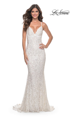 A woman models the La Femme Backless Long Beaded Prom Dress 32309—a sleeveless, floor-length white gown with lace accents and a deep V-neckline—standing against a white background. The La Femme logo is in the top right corner.