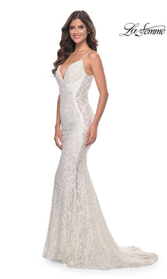 A woman in the La Femme Backless Long Beaded Prom Dress 32309, featuring white lace, thin straps, a deep V neckline, and a slight train, smiles against a white background—an elegant choice for special occasions.