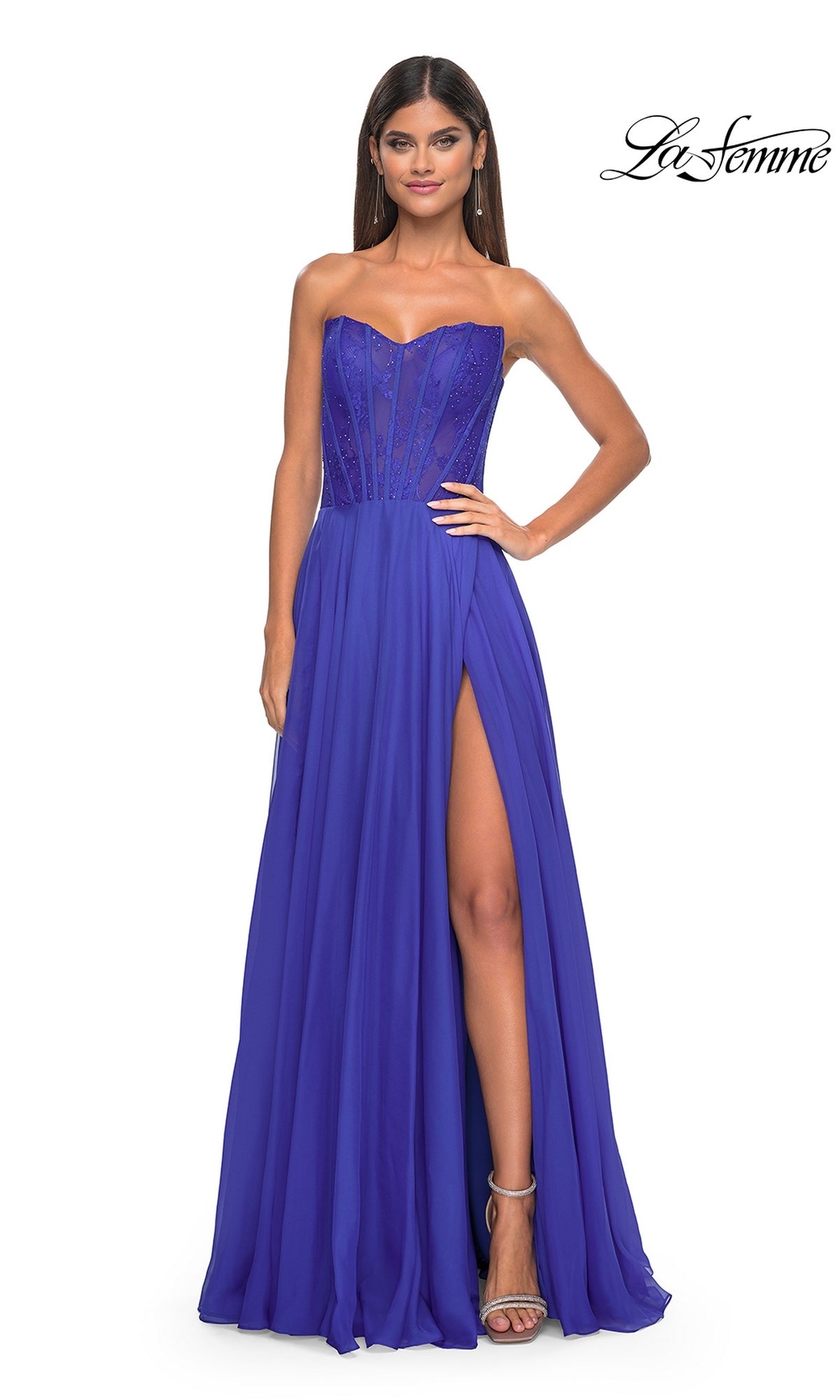 A woman poses against a white background in the La Femme Lace-Bodice Long A-Line Prom Dress 32311, featuring a strapless royal blue design with a sheer corset bodice and high leg slit.
