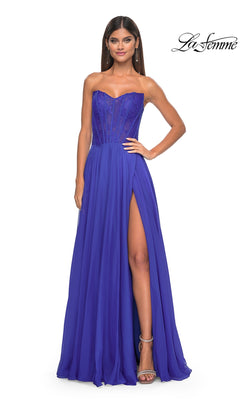 A woman poses against a white background in the La Femme Lace-Bodice Long A-Line Prom Dress 32311, featuring a strapless royal blue design with a sheer corset bodice and high leg slit.