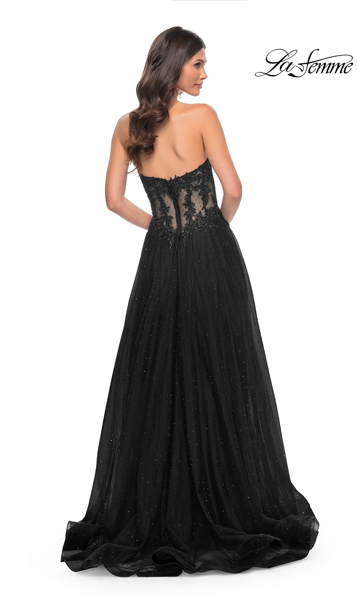 A woman poses against a white background in the La Femme Sheer-Waist Long A-Line Prom Dress 32313, a strapless black gown with a beaded lace bodice, sheer lace back panel, and a flowing skirt for an elegant prom look.