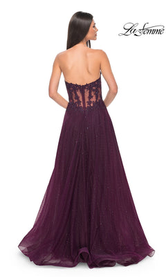 A woman is seen from the back wearing the La Femme Sheer-Waist Long A-Line Prom Dress 32313, featuring a strapless, floor-length deep purple design with a beaded lace bodice and shimmery sheer glitter overlay.
