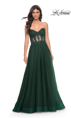 A woman wears the La Femme Sheer-Waist Long A-Line Prom Dress 32313 in dark green, featuring a strapless beaded lace bodice, sheer waist panels, and a flowing skirt.