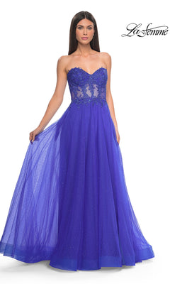 A woman wears the La Femme Sheer-Waist Long A-Line Prom Dress 32313, featuring a strapless royal blue beaded lace bodice and a full tulle skirt. The La Femme logo appears in the top right corner.