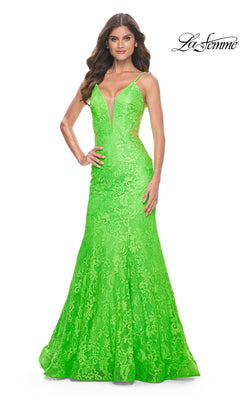 A woman wears the La Femme Bright Long Lace Mermaid Prom Dress 32314, showcasing a vivid green lace mermaid silhouette with a deep V-neckline and thin straps, standing against a white background.