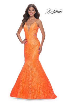 A woman smiles in the La Femme Bright Long Lace Mermaid Prom Dress 32314, featuring thin straps, a deep V-neck, and a lace mermaid silhouette. She stands against a white background with the "La Femme" logo in the top right corner.