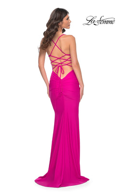 A woman in the La Femme Embellished-Bodice Long Prom Dress 32320, a bright pink floor-length gown with an open back, crisscross straps, fitted silhouette, ruched accents, and an embellished bodice.