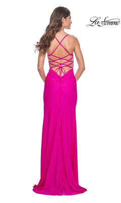 A woman stands with her back to the camera in the La Femme Open-Back Bright Long Prom Dress 32321, featuring a ruched back, crisscross spaghetti straps, and delicate beaded floral embroidery.