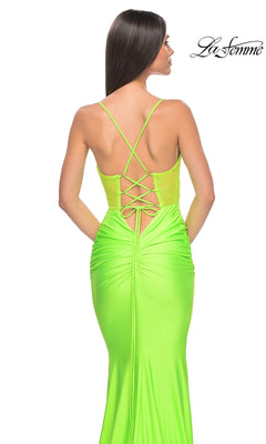 A woman is seen from behind in the La Femme Sheer-Bodice Long Prom Dress 32322, a bright neon green gown featuring thin crisscross straps and a lace-up back.