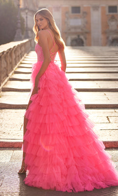 A woman stands on outdoor steps, looking over her shoulder in the La Femme Long Tiered A-Line Prom Dress 32335—a bright pink, floor-length gown with ruffles and a fitted strappy bodice.