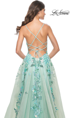 A woman stands with her back to the camera in the La Femme Sequin-Print Long Green Prom Dress 32347, featuring a light green floral sequin design, lace-up open back, and a flowing A-line skirt with intricate detailing.