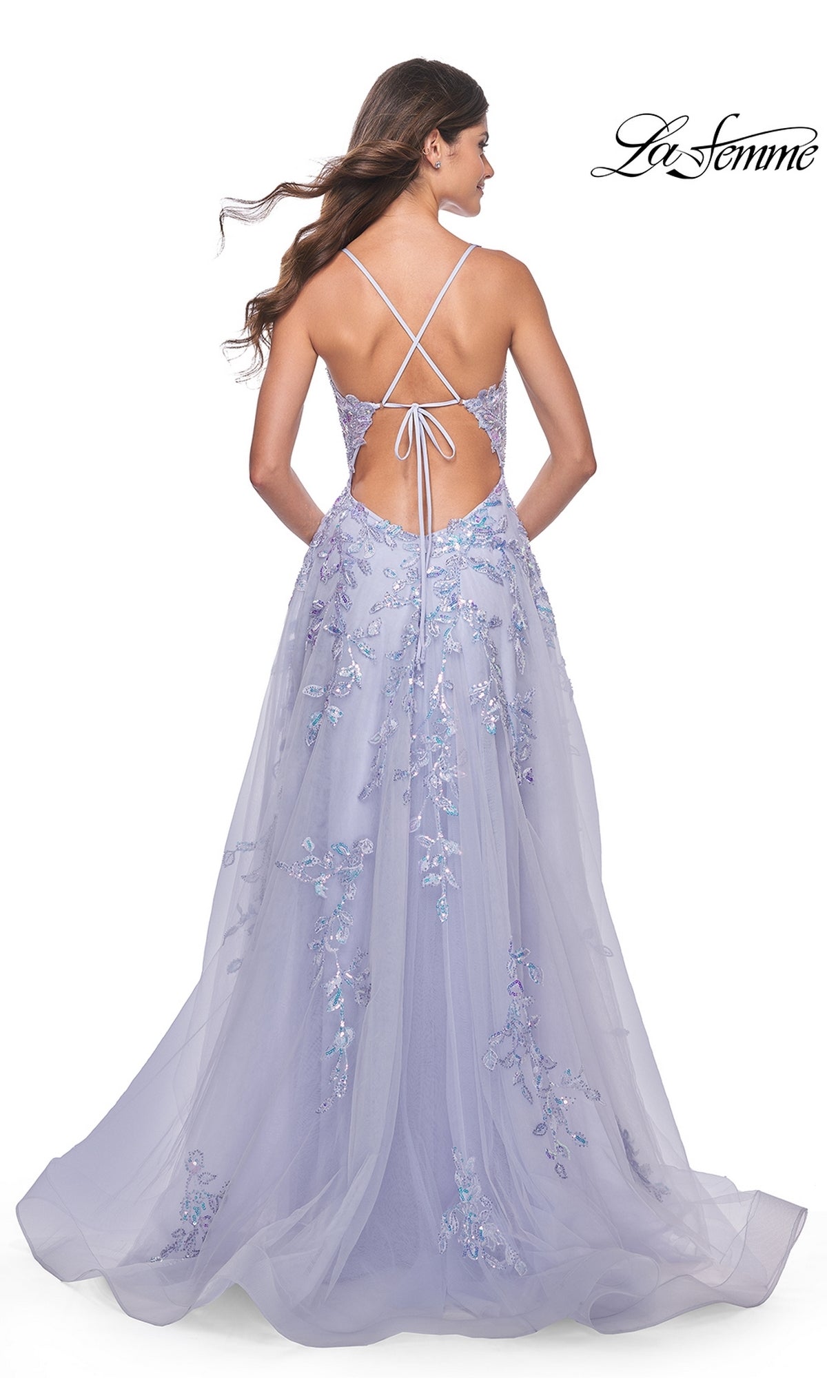 A woman stands facing away in the La Femme Long Periwinkle A-Line Prom Dress 32349, featuring sequin-lace floral embroidery and a lace-up open back. The La Femme logo appears in the top right corner.