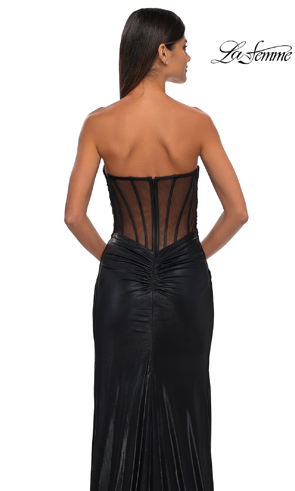 Woman in a strapless black metallic La Femme 32375 prom dress with sheer back and ruched details, facing away from the camera; 