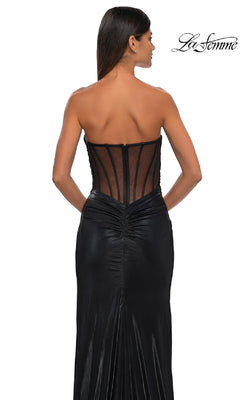 Woman in a strapless black metallic La Femme 32375 prom dress with sheer back and ruched details, facing away from the camera; "La Femme" logo appears in the top right corner.