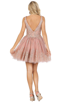 A woman with blonde hair wears the Silver-Beaded Short Babydoll Hoco Dress 3237, a sleeveless A-line party dress with sparkling beadwork and a deep V-back. She pairs it with glittery high heels and faces away from the camera.