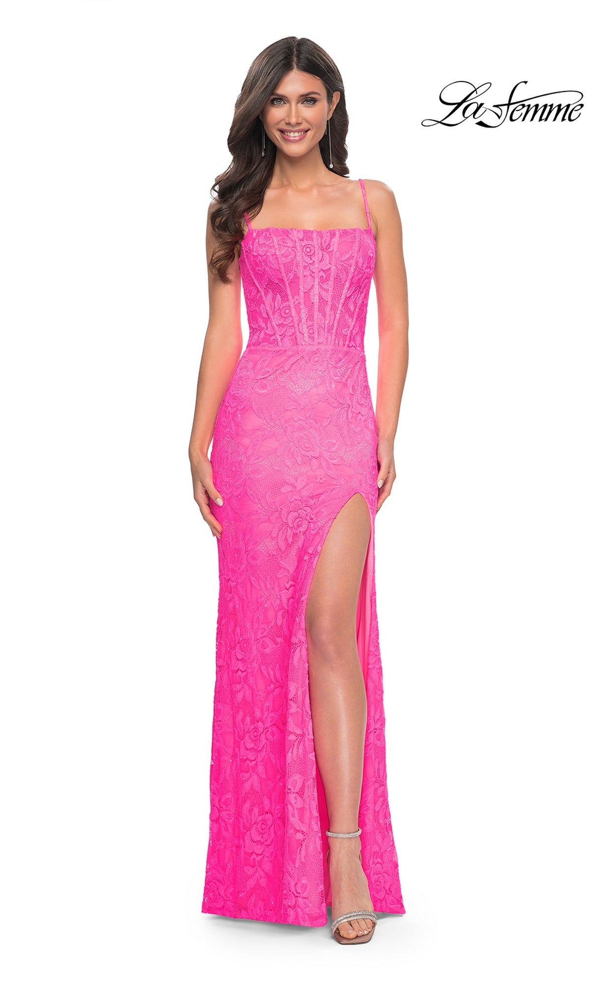 A woman smiles in the Neon Pink Long Lace Prom Dress: La Femme 32423, featuring spaghetti straps, lace details, and a high slit. 