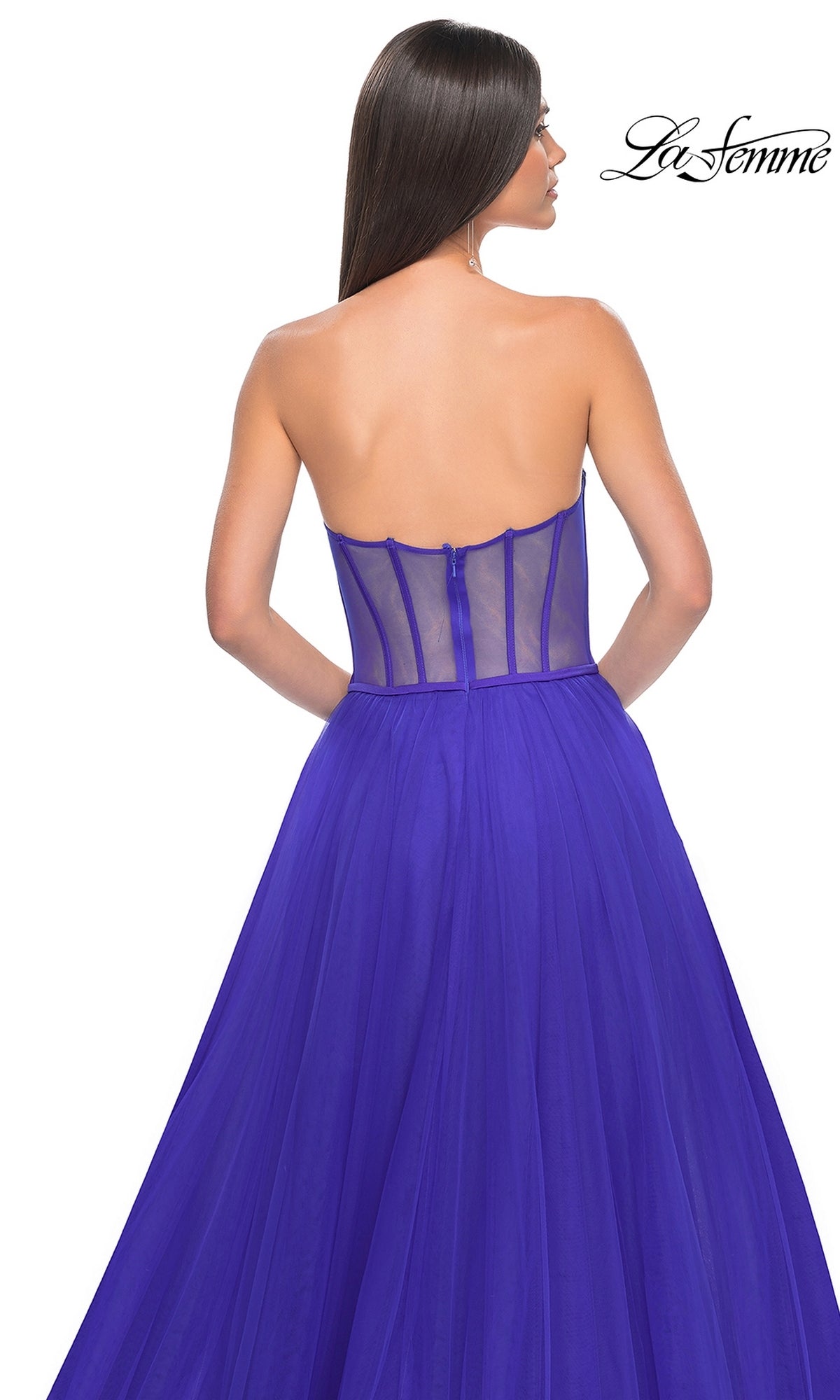 A woman is seen from behind in the La Femme 32424 strapless long tulle prom dress, featuring a royal blue corset-style sheer-back bodice and a full flowing skirt, set against a white background.