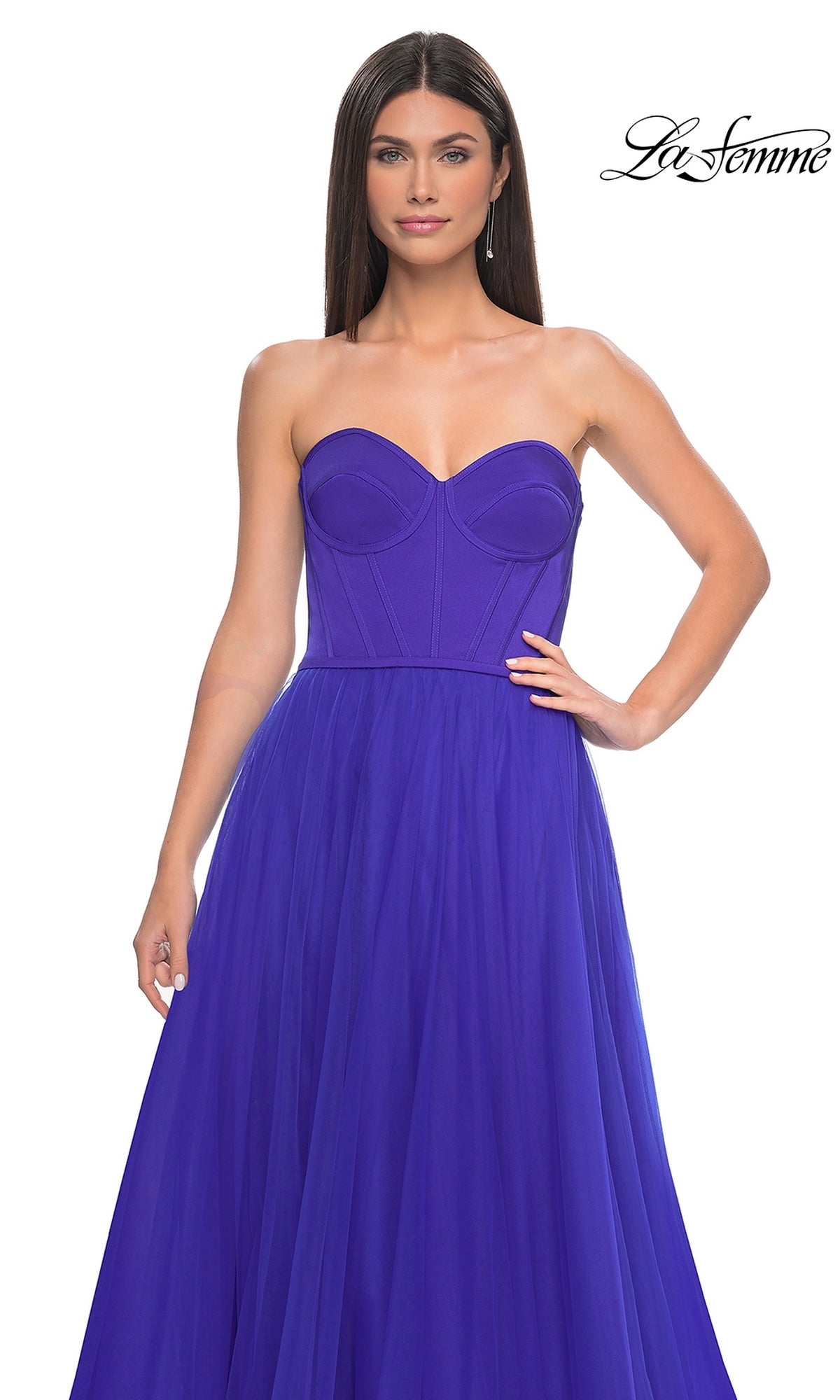 A woman models the La Femme 32424: a strapless long tulle prom dress in bright purple with a corset-style bodice and flowing A-line skirt, shown against a plain white background.