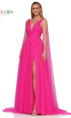 A woman wears the Colors Dress 3242, a Classic Long Prom Ball Gown in hot pink with a v-neck, sleeveless design, floor-length sheer tulle, deep front slit, and cape-like shoulder extensions.