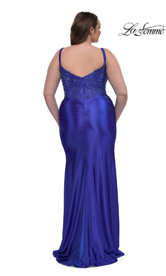 A woman in the Plus-Size Long Satin Prom Dress La Femme 32430, featuring a fitted floor-length royal blue design with rhinestone beaded bodice, thin straps, a slight train, and elegant shimmer—perfect for any special occasion.