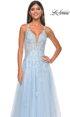 A woman in the Sheer-Waist Long A-Line Prom Dress (La Femme 32438) with light blue embroidered lace, a sheer bodice, and tulle skirt stands smiling. The sleeveless gown is elegant, with the La Femme logo in the top right corner.